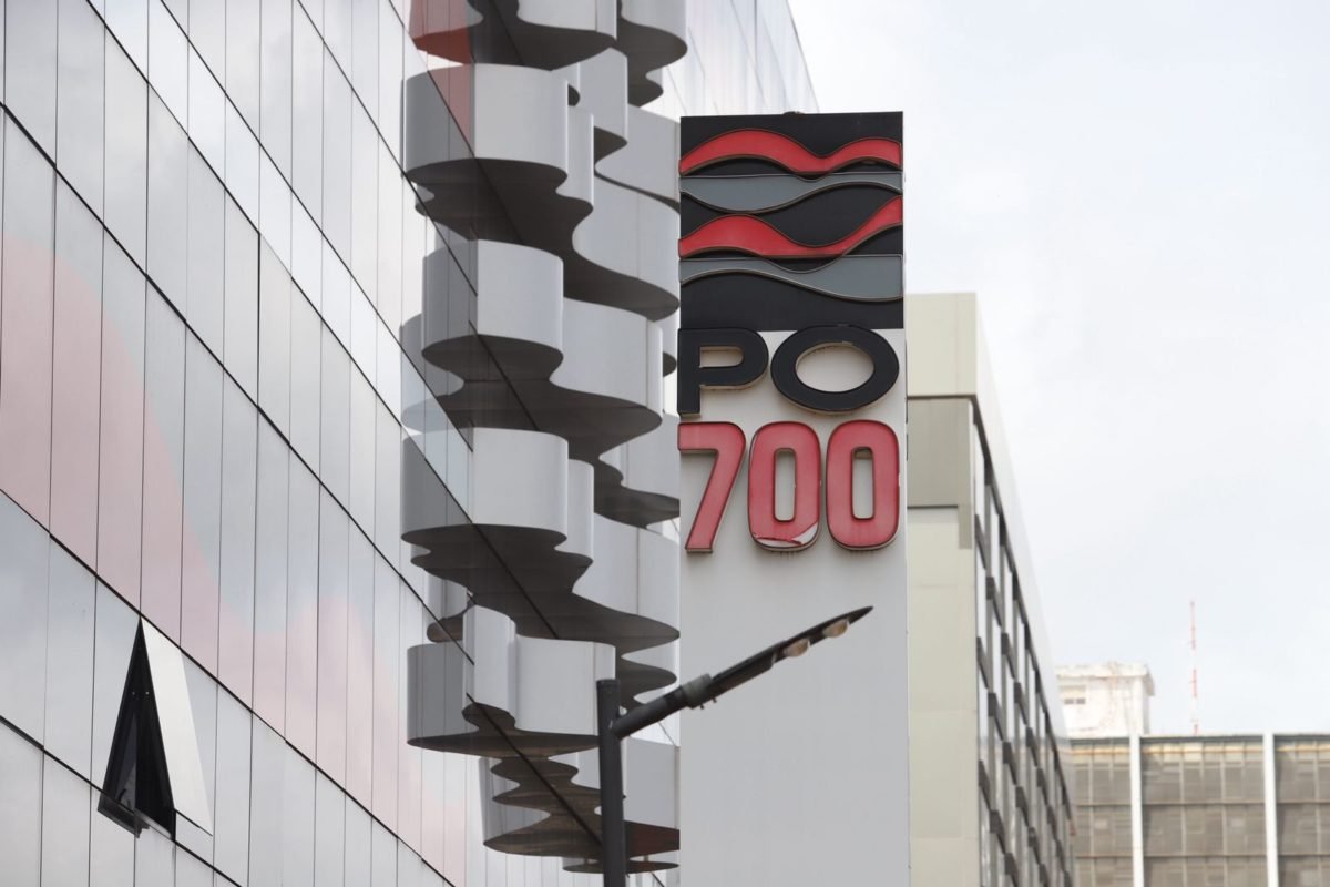 Foto colorida de fachada de prédio com placa escrito PO 700