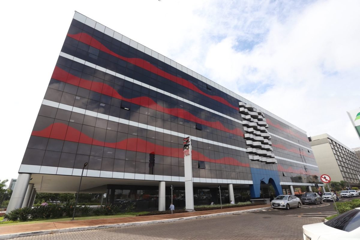 Foto colorida de fachada de prédio vermelho e prédio