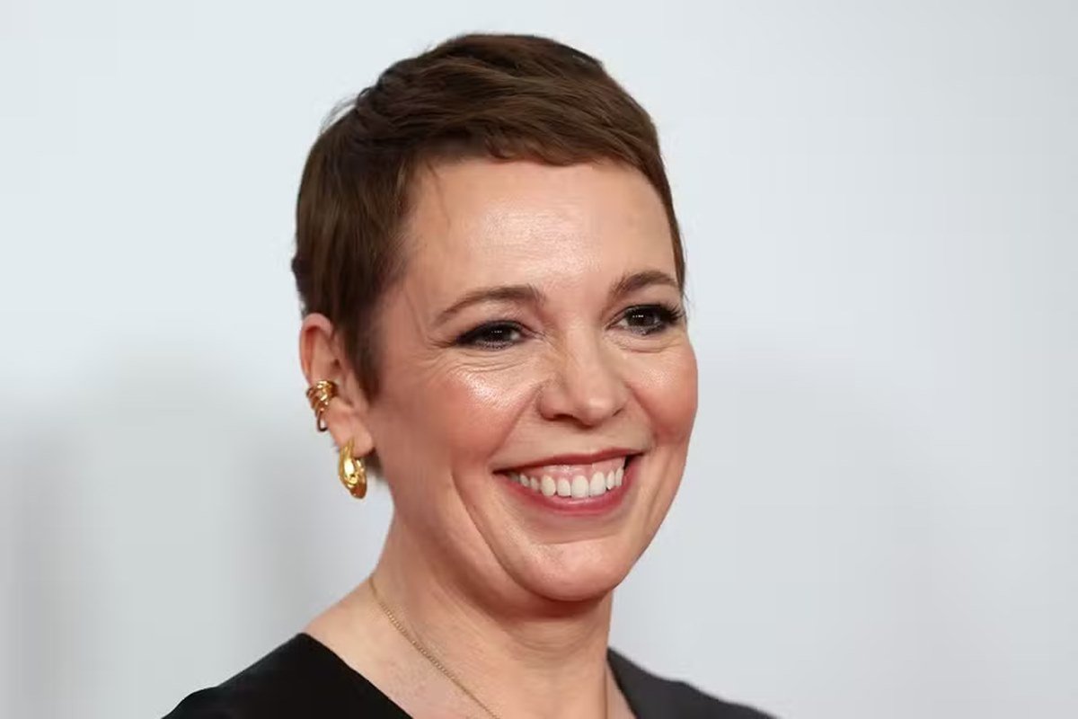 Foto colorida de Olivia Colman. Ela é uma mulher branca, de cabelo curto e está sorrindo - Metrópoles