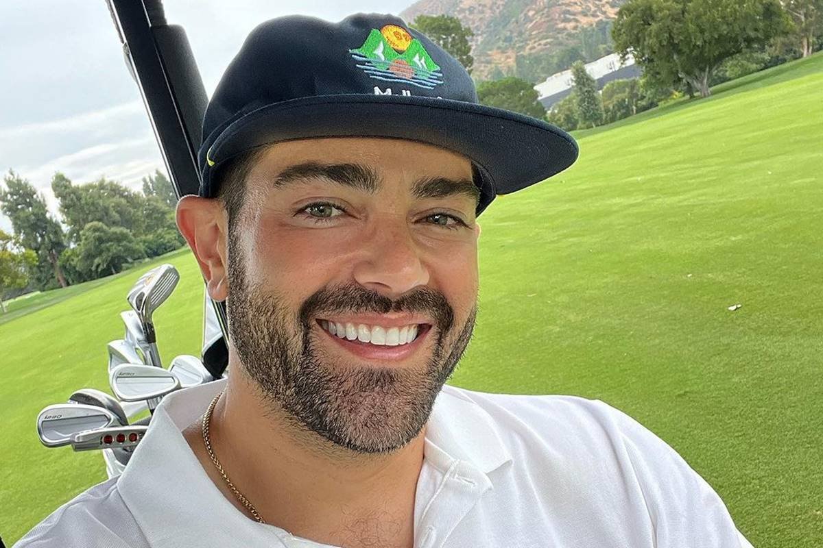 foto colorida de homem branco sorrindo e vestido com blusa branca e boné - metrópoles