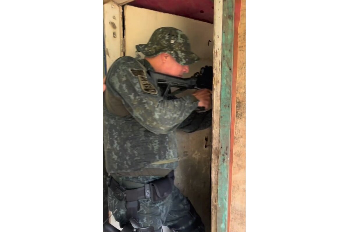 Foto colorida de policial militar, com roupa camuflada, empunhando fuzil - Metrópoles