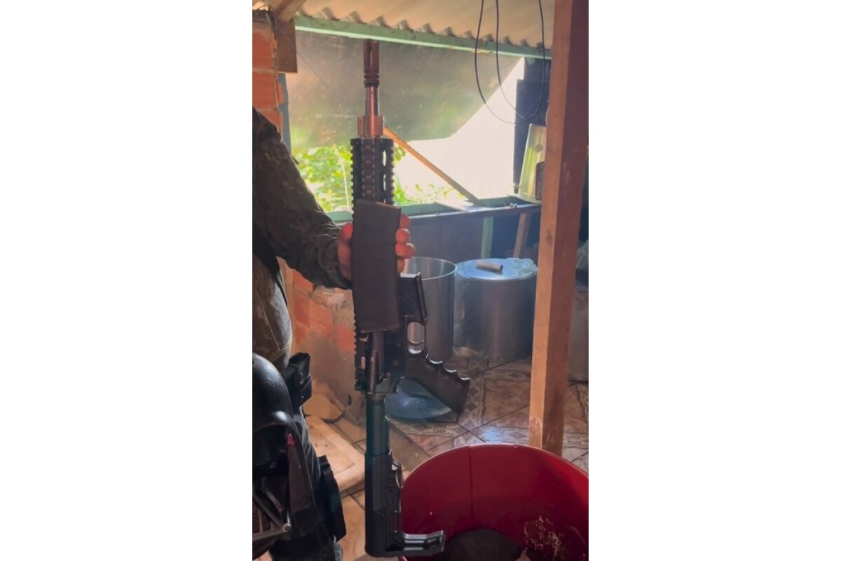 Policial com roupa camuflada mostra fuzil apreendido - Metrópoles
