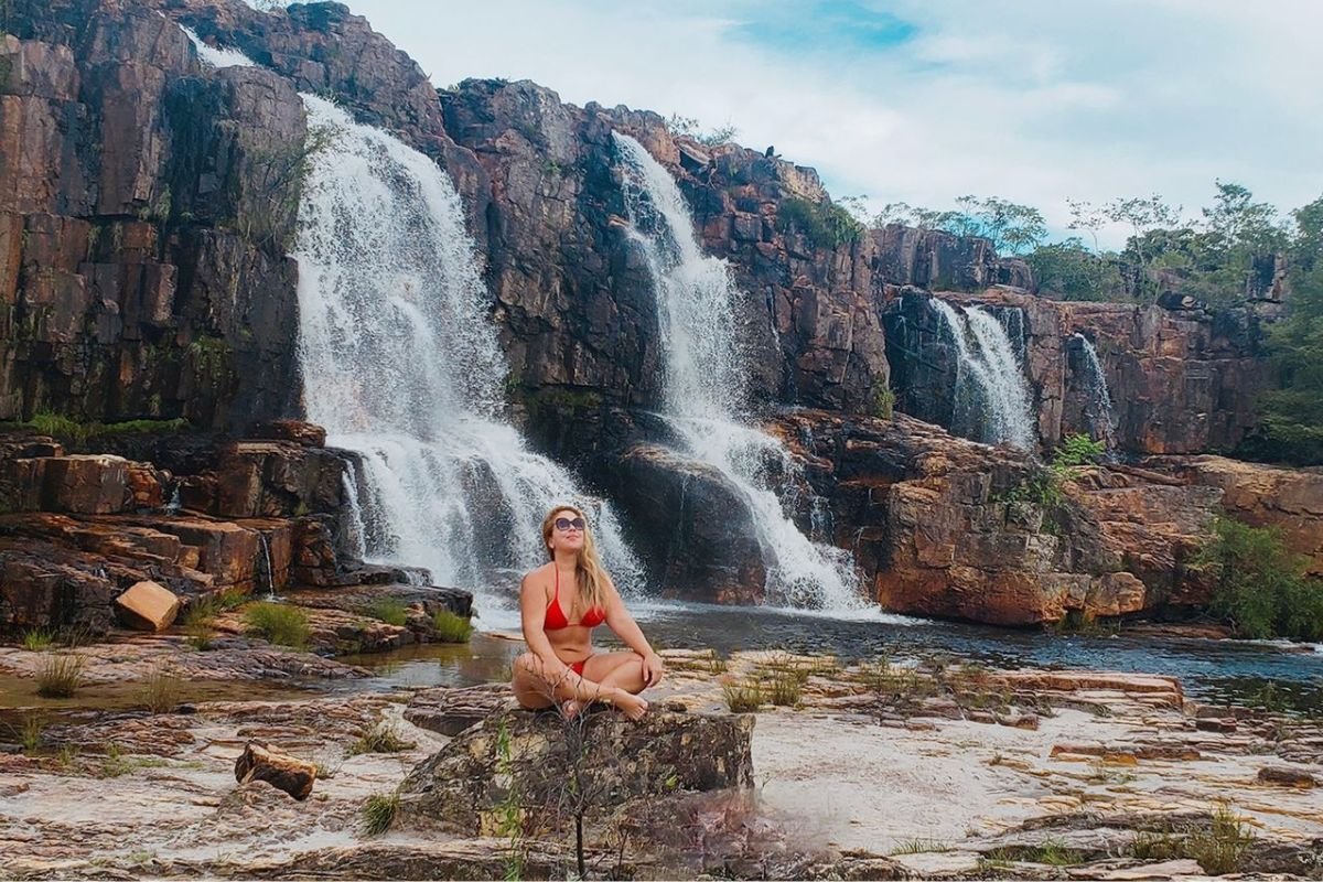 Foto colorida de uma mulher na cachoeira - Metrópoles
