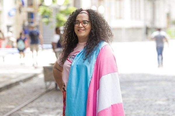 Imagem colorida de Luana Maria com a bandeira trans - Metrópoles