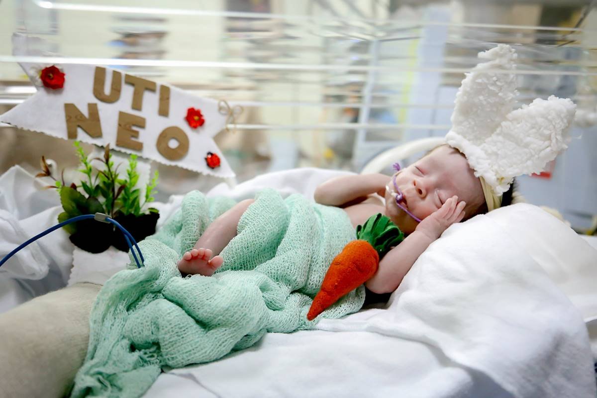 Foto colorida de bebê com fantasia de coelhinho da páscoa