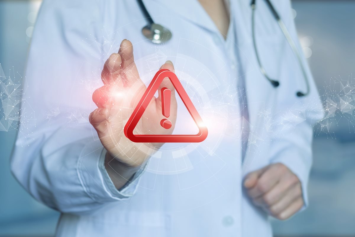 Ilustração colorida com pessoa real, vestida de branco, representando um médico com sinal de exclamação em vermelho em frente - Metrópoles.