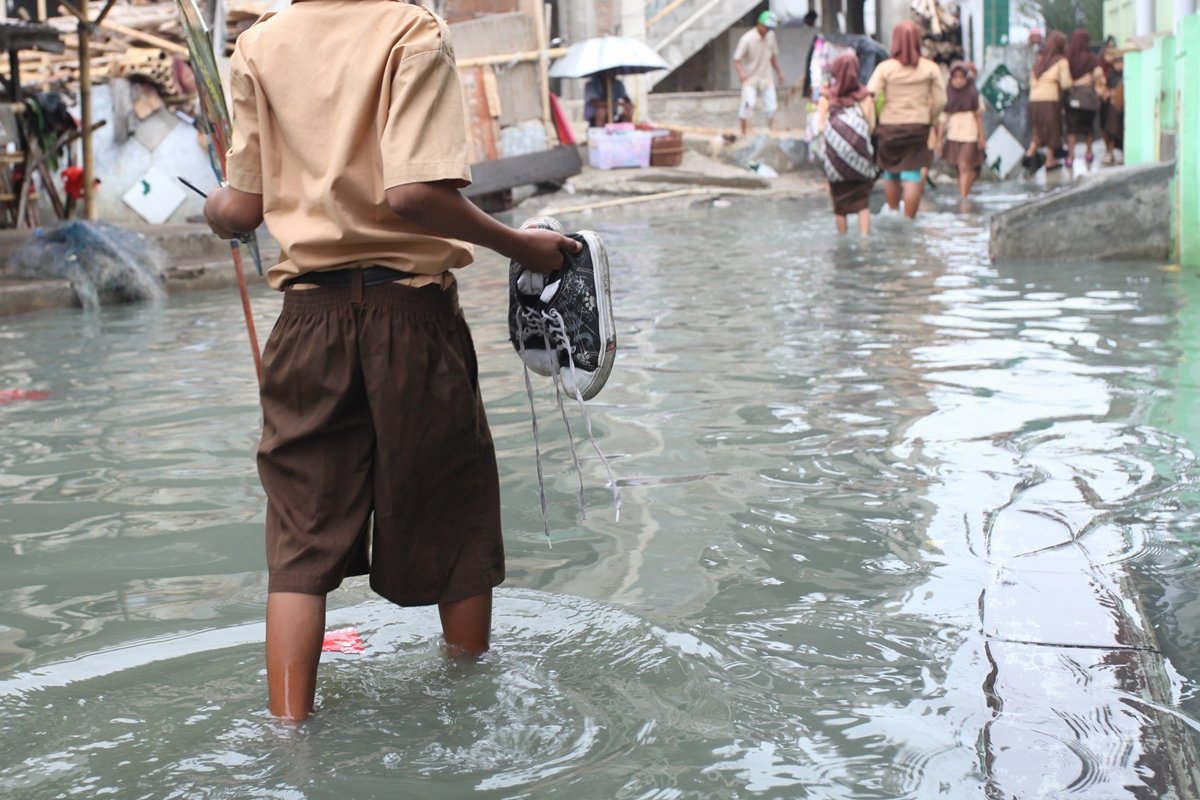 Foto de rapaz segurando sapatos em alagamento - Metrópoles