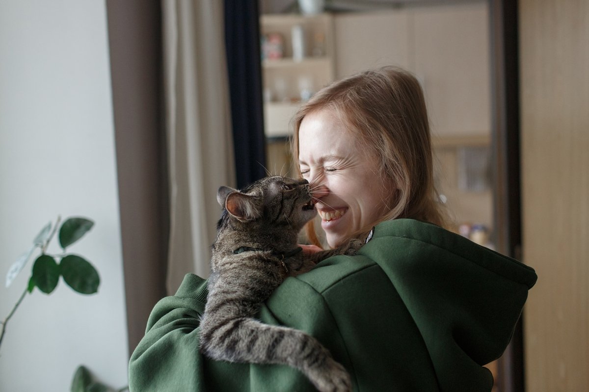Foto colorida de mulher interagindo com gato - Entenda o que conviver com um gato faz com o seu cérebro e com o dele - Metrópoles