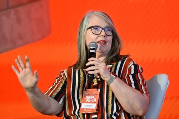 Denise palestrando com microfone na mão no Talk Educação do Amanhã