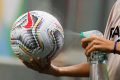 Gandula limpa a bola com álcool antes de retorna-la para o jogo. Protocolos tomados pela Conmebol durante a pandemia do Corona vírus. copa america