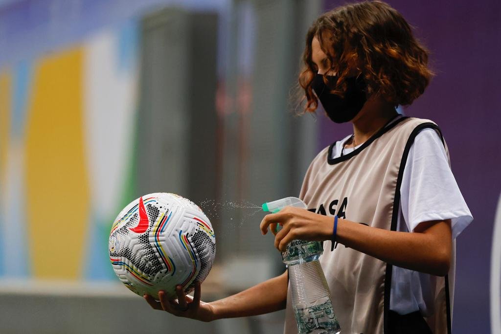 Gandula limpa a bola com álcool antes de retorna-la para o jogo. Protocolos tomados pela Conmebol durante a pandemia do Corona vírus. copa america