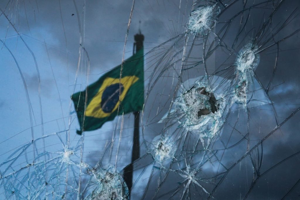 Vidro quebrado por bolsonaristas com bandeira do brasil ao fundo - Metrópoles