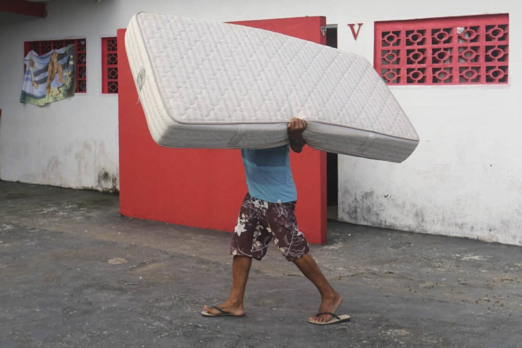 Imagem colorida com homem carregando colchão após fortes chuvas no Litoral Norte de SP - Metrópoles